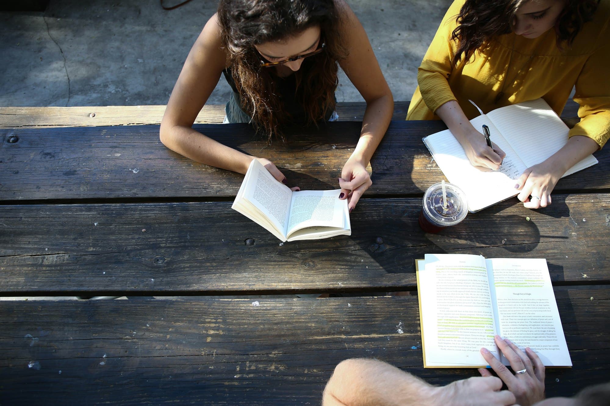 A study group reading and taking notes at a picnic table