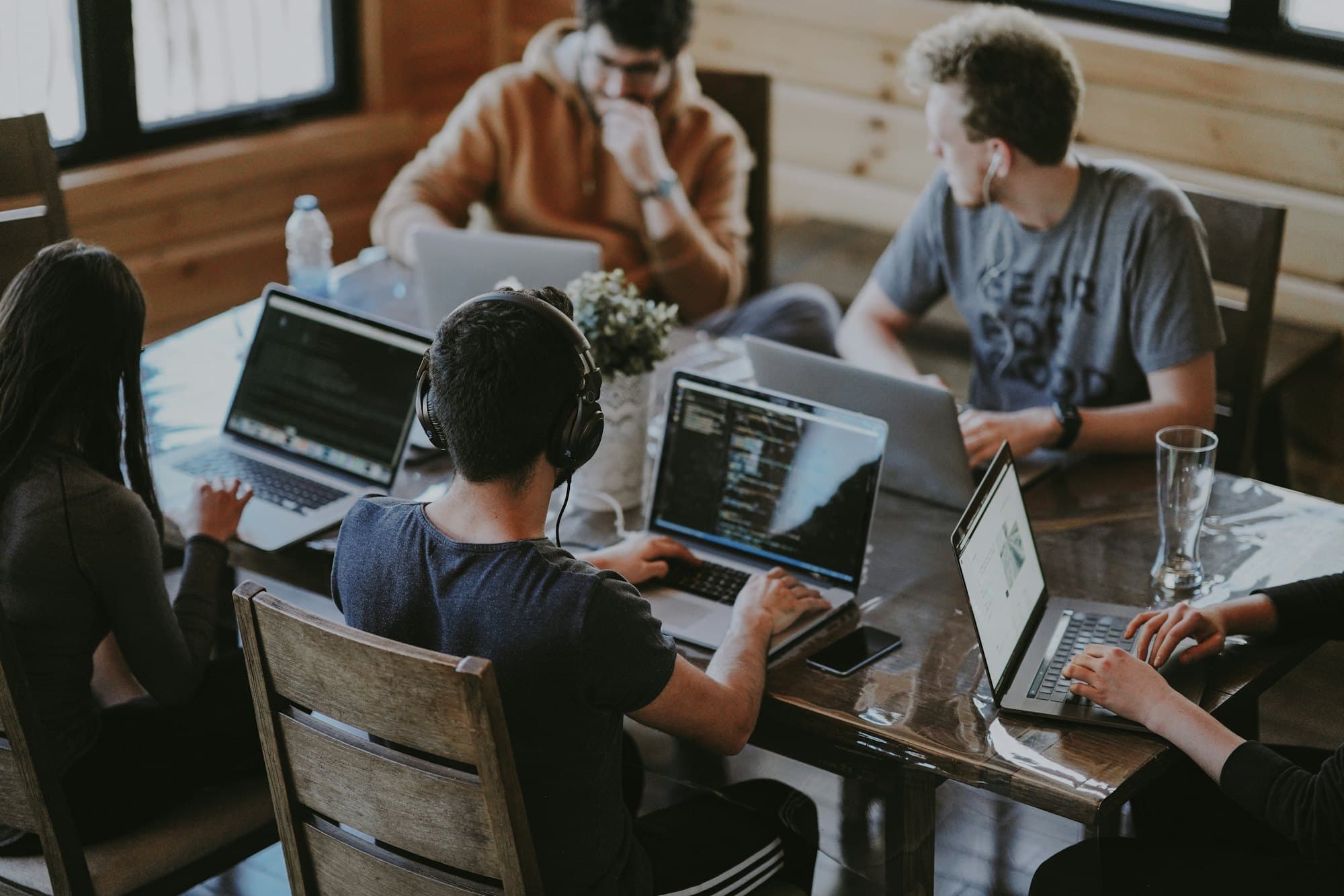 Developers working on laptops around a wooden table